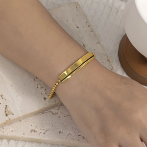 Dettaglio del bracciale a sfere placcato oro 18K con barra rettangolare indossato al polso