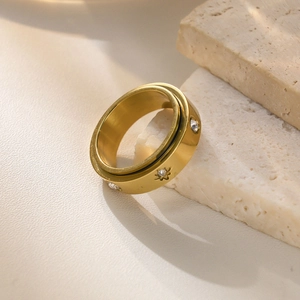 Detail of a gold spinner ring with sparkling zircon inlays on textured stone