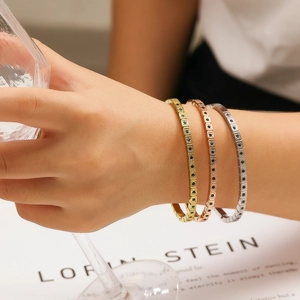 Dettaglio di tre bracciali in acciaio inossidabile con zirconi neri impilati sul polso