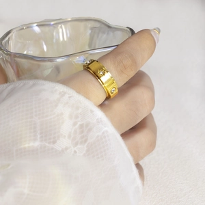 Detail of gold rotatable ring with star-shaped engravings and zircon stones on a model