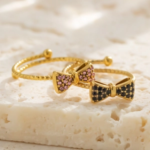 Detailaufnahme der goldenen Schleifenringe mit rosa und schwarzen Kristallen