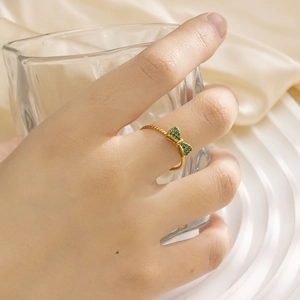 Detail der goldenen Schleife mit grünen Zirkonia auf gedrehtem Seilringband