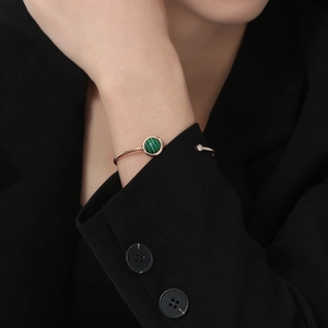 Dettaglio del bracciale rigido in oro rosa con malachite e zircone su blazer nero