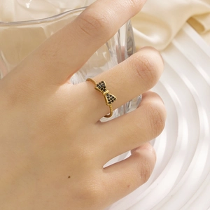 Detail eines goldenen Schleifenrings mit schwarzen Zirkon-Steinen und gedrehtem Band