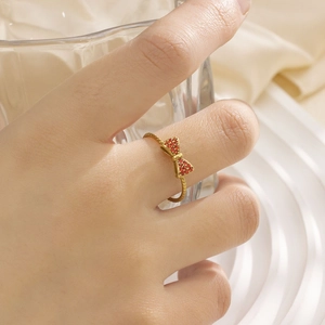 Detail eines vergoldeten Rings mit funkelnder roter Strass-Schleife am Finger