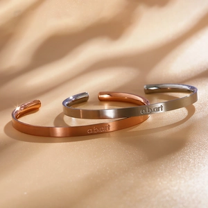 Dettaglio dei bracciali aperti a forma di C in finitura opaca spazzolata oro rosa e argento