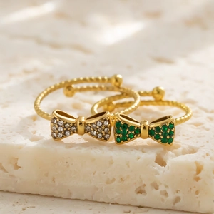Elegante goldene Schleifenringe mit Smaragd- und Zirkonsteinen auf gedrehtem Band