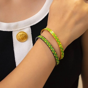 Dettaglio di bracciali smaltati con trama intrecciata su finitura metallica oro e nera