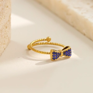 Detailansicht eines vergoldeten Schleifenrings mit blauen Kristallen und gedrehter Ringschiene