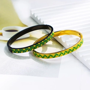 Dettaglio di bracciali rigidi in smalto con motivo a spina di pesce verde e giallo