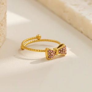 Detailansicht eines goldenen Schleifenrings mit rosa Kristallen und spiralförmigem Band