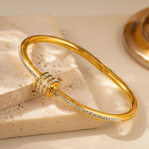 Detail eines goldenen Bambus-Armreifs mit Zirkonia-Steinen auf strukturierten Steinen