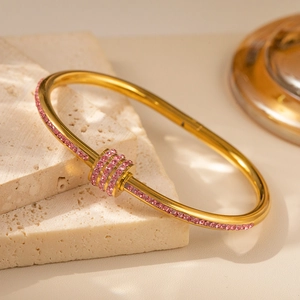 Detaillierte Makroansicht eines goldenen Armbands im Bambus-Stil mit rosa Zirkonia-Besatz