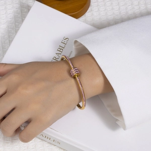 Detail eines goldenen Armreifs im Bambus-Stil mit rosa Zirkonia-Glückskugeln