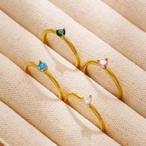 Set de cuatro anillos minimalistas de titanio dorado con gemas de colores en estuche