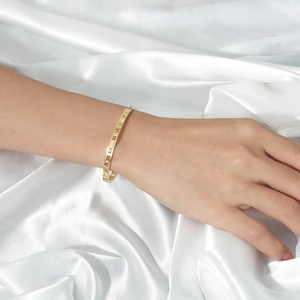 Dettaglio del bracciale in acciaio titanio dorato con numeri romani e zircone su seta