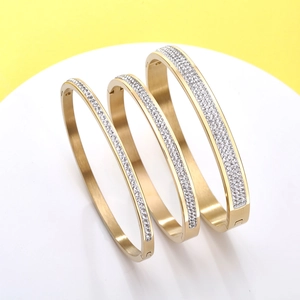 Detailed view of three stackable gold-plated stainless steel bangles with pavé set zircons