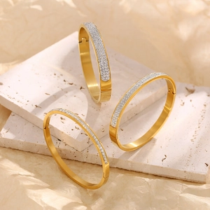 Close-up of gold-plated stainless steel bangle with pavé zirconia crystals and snap closure