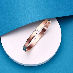 Macro detail of brushed rose gold bangle featuring three inset sparkling cubic zirconia