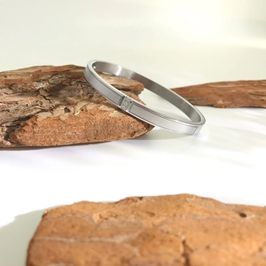 Detail of silver stainless steel bangle with rectangular patterns and three zircons