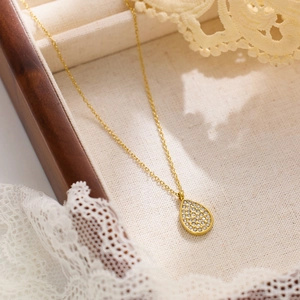 Collier élégant à pendentif goutte dorée avec oxydes de zirconium sur fond de dentelle