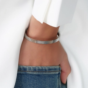 Detail of silver titanium steel bracelet with geometric patterns worn by a model