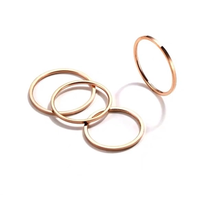 Dettaglio macro di quattro anelli impilabili minimalisti in oro rosa su sfondo bianco