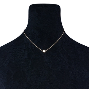 Detailed close-up of a minimalist gold heart pendant necklace on a black lace display