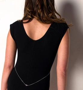 Detailed view of a minimalist silver body chain featuring a lobster clasp on a black dress