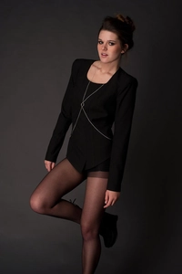 Detailed view of a silver-tone minimalist body chain with a central metal ring over a suit