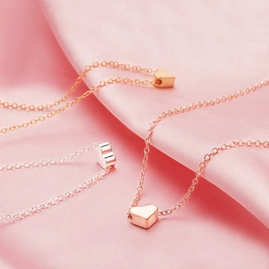 Detailed close-up of three solid heart-shaped necklaces in gold, silver, and rose gold