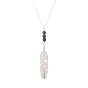 Macro shot of silver feather pendant necklace featuring black lava stone beads details