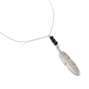 Detailed macro view of the silver feather pendant and black volcanic beads on the long necklace