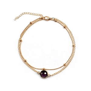 Minimalist gold dual-layer anklet featuring a round purple gemstone and bead chain design