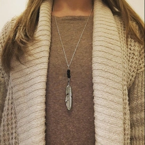 Vintage silver feather pendant necklace with black beads on model in warm casual attire