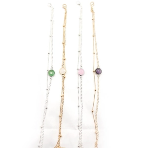 Detail of double-layer ankle bracelet with round gemstones in green, pink, white, and purple