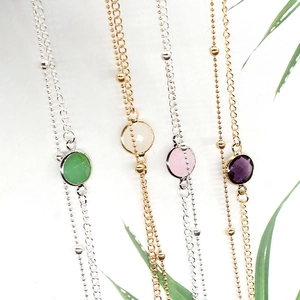Detail of double-layer chain anklet featuring round cut gemstones in four distinct colors