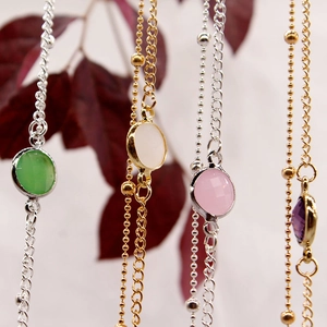 Detailed shot of delicate gold and silver alloy chains with round colorful gemstones