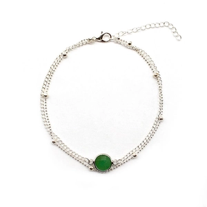 Close-up of double-layer silver anklet with a round green gemstone and lobster clasp detail