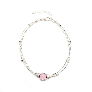 Detail of silver layered anklet featuring a pink round gemstone and adjustable lobster clasp