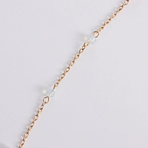 Détail macro d'une chaîne dorée avec des perles de cristal irisées et des facettes