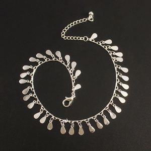 Detailed view of silver-tone anklet with multiple small teardrop-shaped metal charms