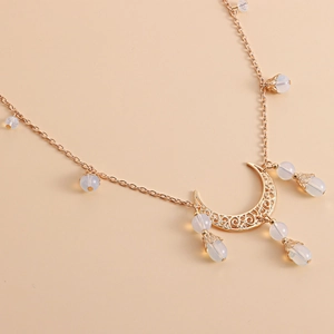 Chaîne de tête bohème avec croissant de lune doré et perles blanches sur fond beige