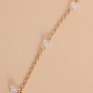 Détail de la chaîne de tête dorée avec perles de cristal facettées et maillons ovales