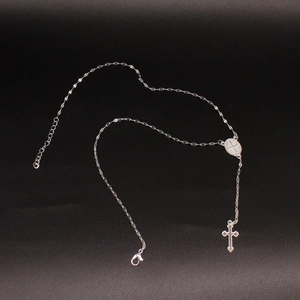 Detailed view of silver cross necklace with religious medal and lobster clasp closure