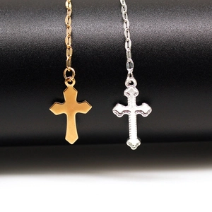 Detailed view of polished gold and textured silver cross necklaces on a bicolor background
