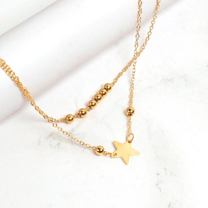 Detail of a layered gold anklet featuring tiny beads and a minimalist star pendant