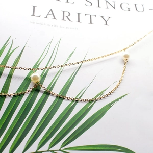 Detailansicht einer eleganten mehrlagigen Gold-Perlen-Taillenkette auf weißem Magazin