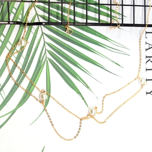 Detailansicht der mehrlagigen goldenen Körperkette mit eleganten Perlen und Karabiner