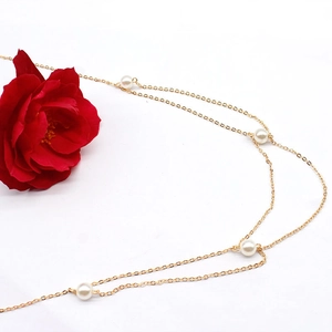 Detail einer mehrlagigen goldenen Taillenkette mit eleganten weißen Perlen und Design